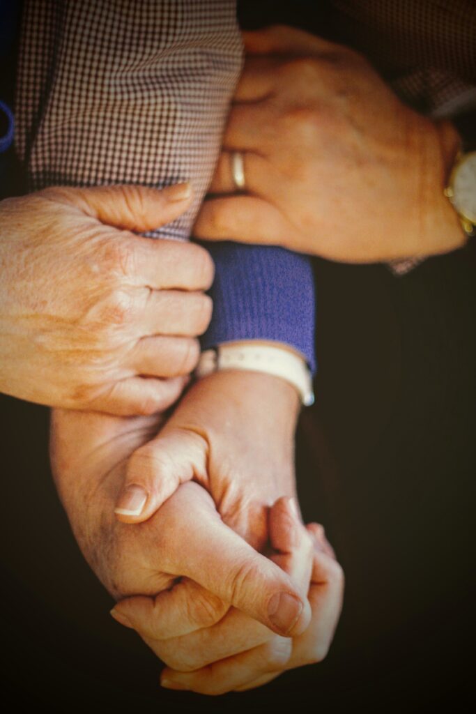 elderly patient holding hands with carer