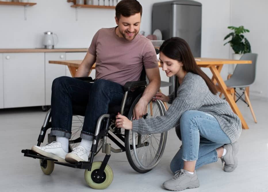 carer helping disabled man on wheelchair