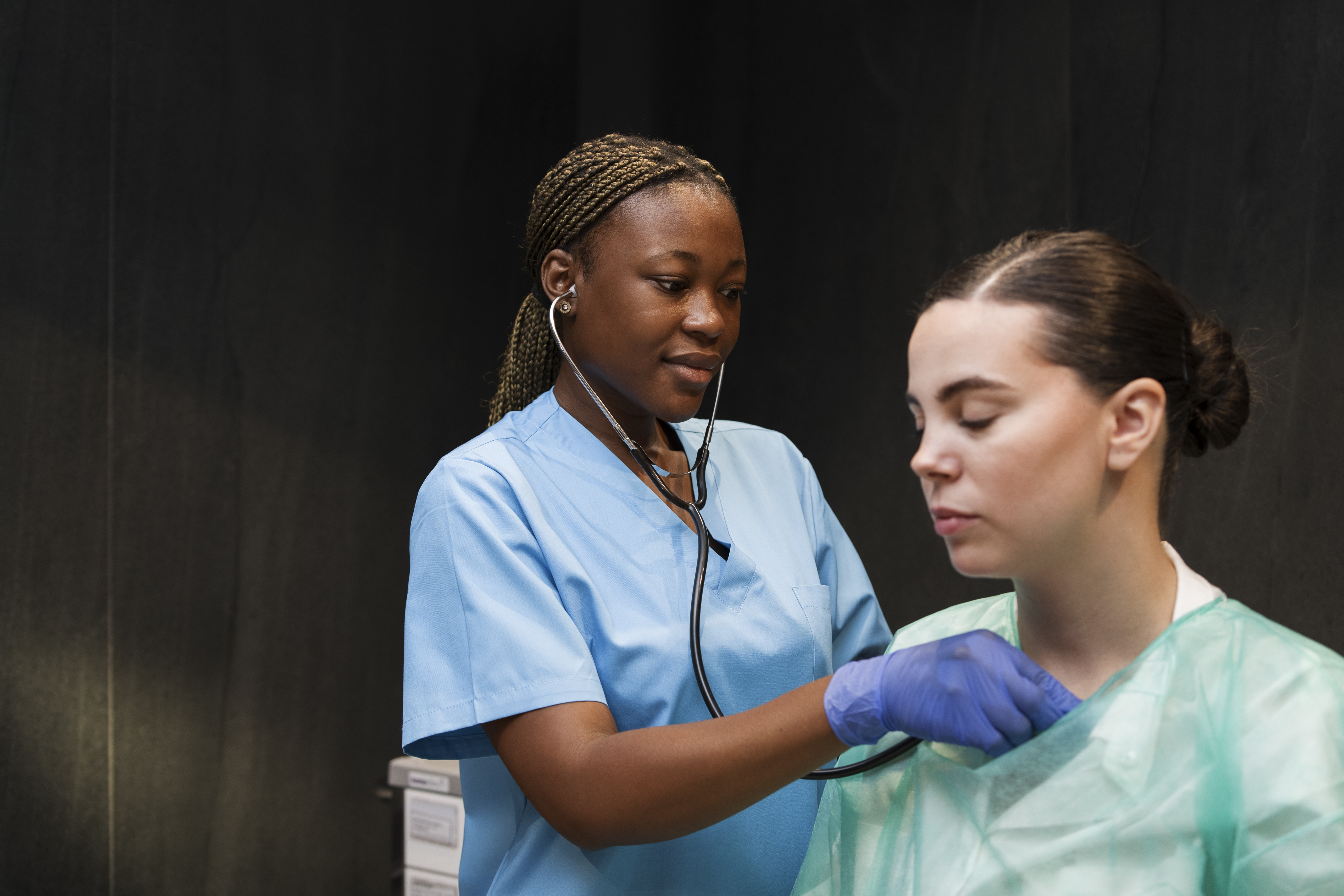 African nurse with stethoscope hearing patient heartbeat