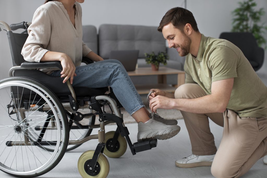 carer tying up patient shoes on wheelchair